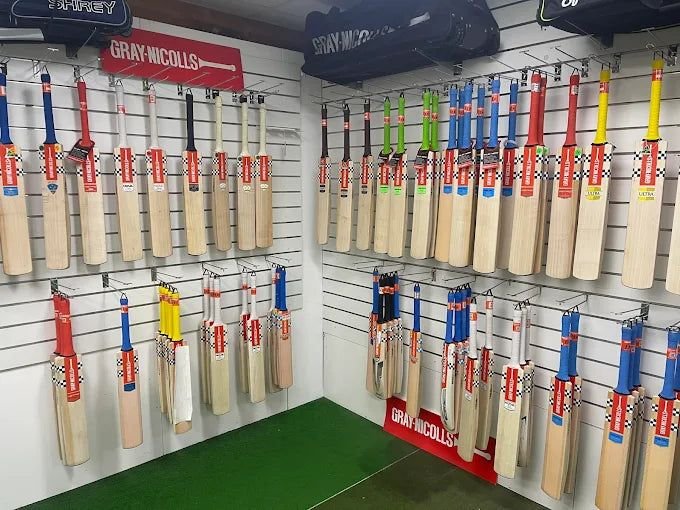 Cricket bat, ball and stumps laid out on the pitch
