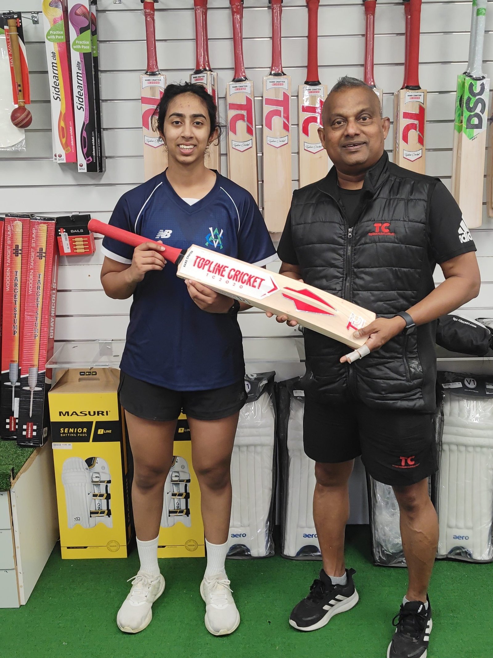 Coach presenting a young player with a Topline Cricket bat